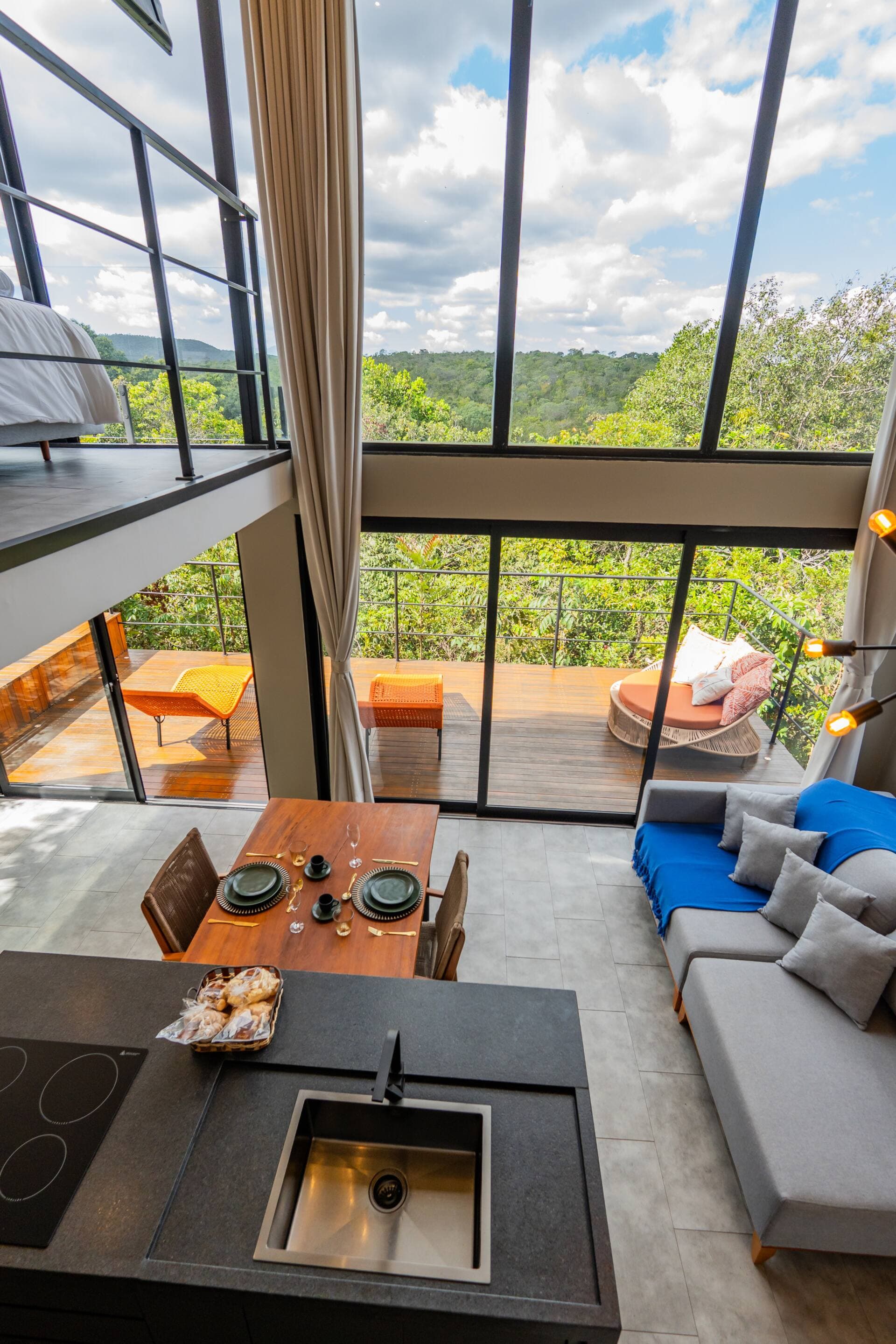 Sala e cozinha integradas, com mezanino do quarto ao fundo e vista para o horizonte