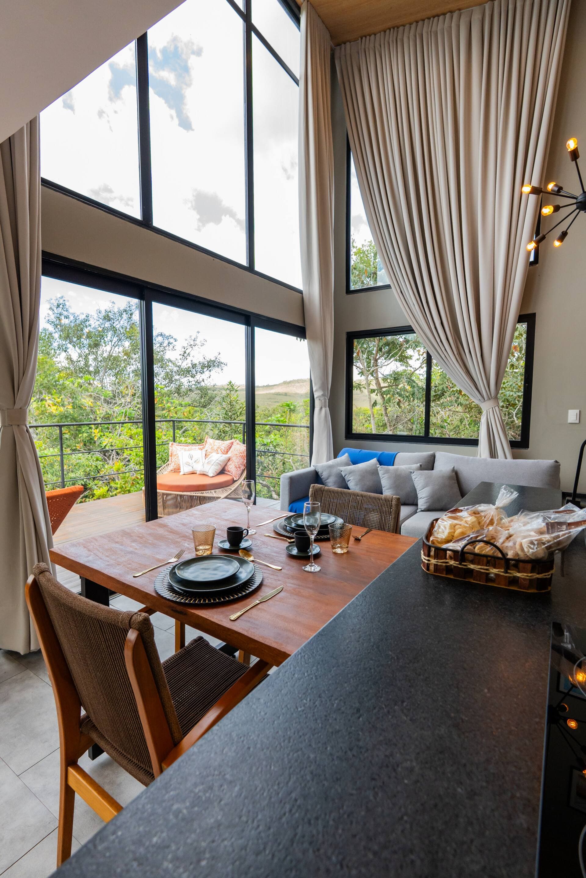 Bancada da cozinha com pia e torneira preta, sofá azul e mesa posta ao fundo